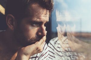 Man looking out window knowing he needs full body drug detox at mens rehab